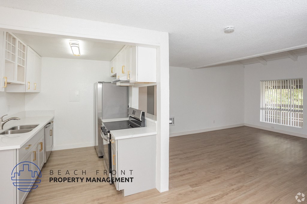 A kitchen with white cabinets and a wooden floor.