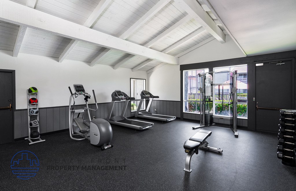 A gym with a variety of equipment including treadmills, weights, and exercise machines.