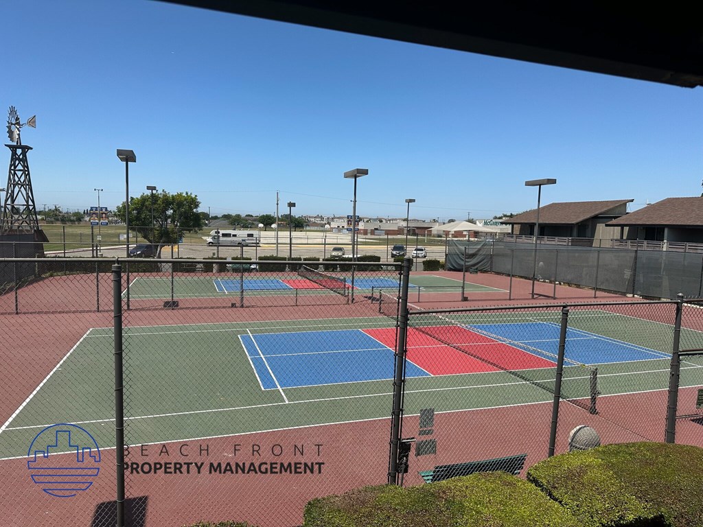 A tennis court with the words "Beach Front Property Management" on the net.