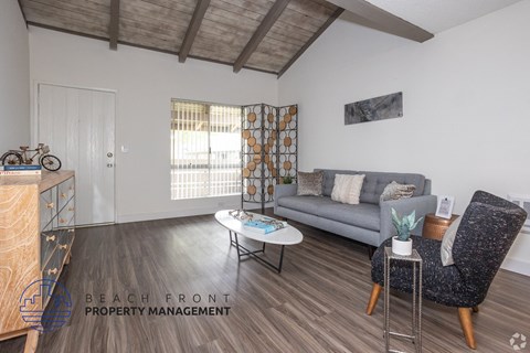 A living room with a grey couch, a coffee table, and a chair with a patterned cushion.