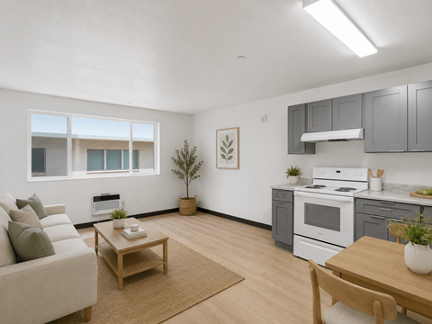 A living room with a couch, a table, and a kitchen area in the background.