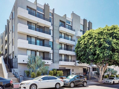 a large white apartment building with cars parked in front of it