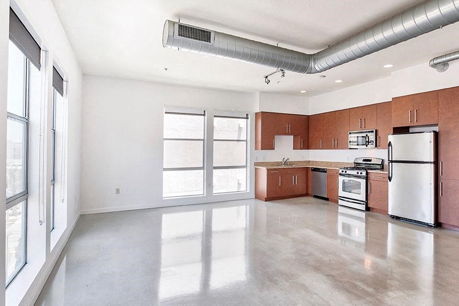 an empty kitchen with stainless steel appliances and wood cabinets