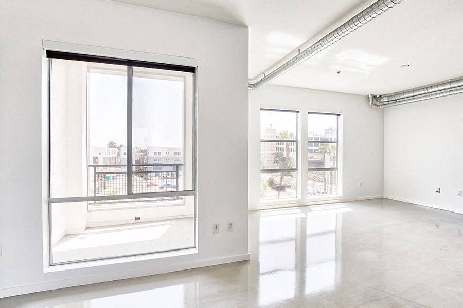 an empty room with large windows and white walls