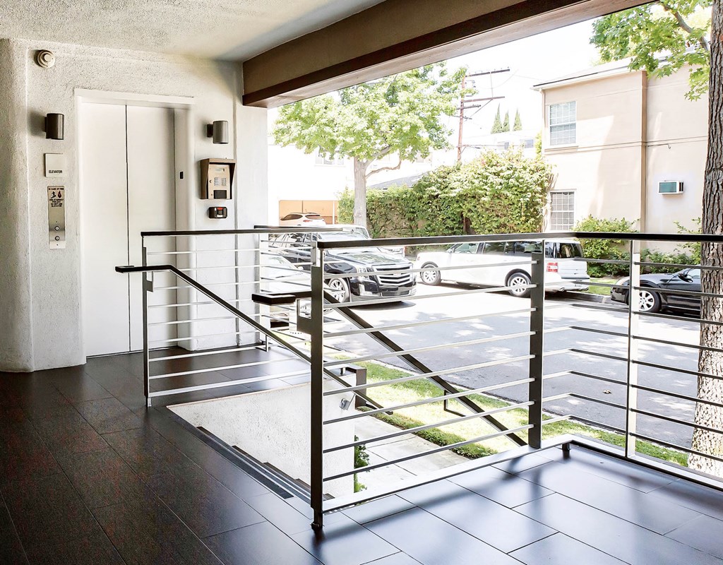 the entrance to an apartment building with a railing and a parking lot