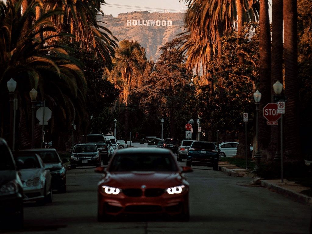 a red car driving down a street with palm trees