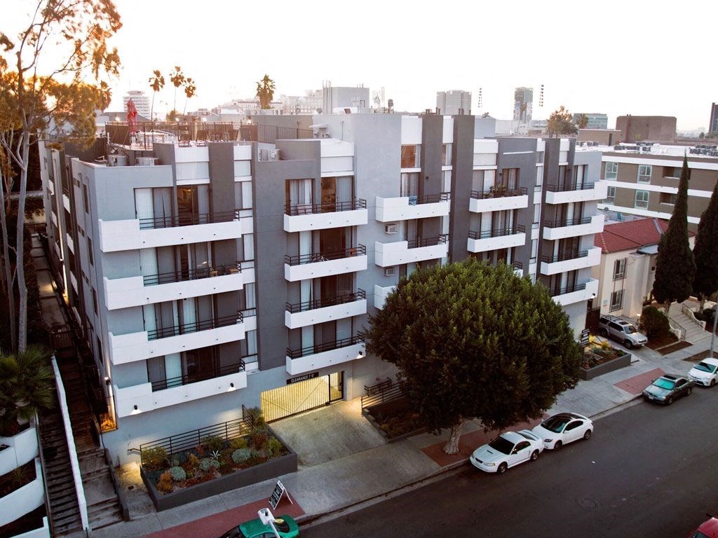 an aerial view of an apartment building with cars parked in front