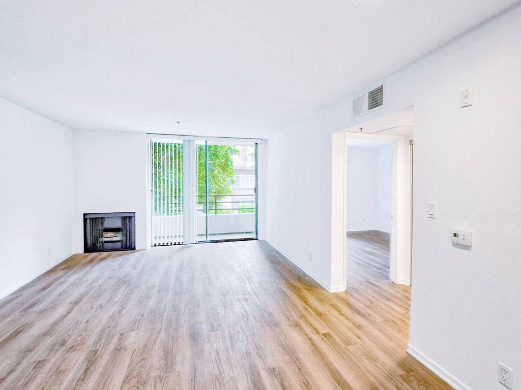 an empty living room with a wood floor and a fireplace