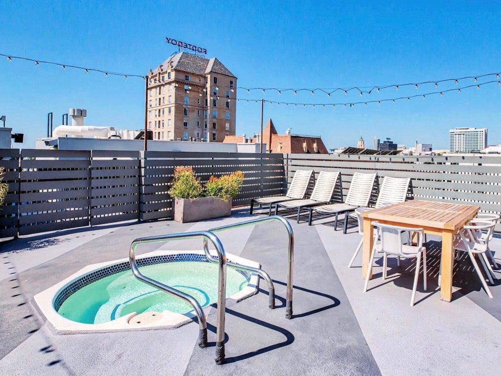a hot tub on the roof of a building with a table and chairs
