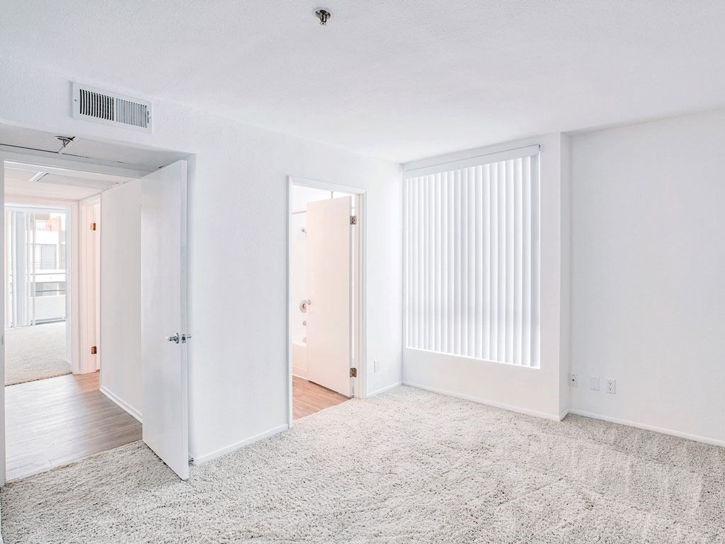 an empty living room with white walls and a white rug