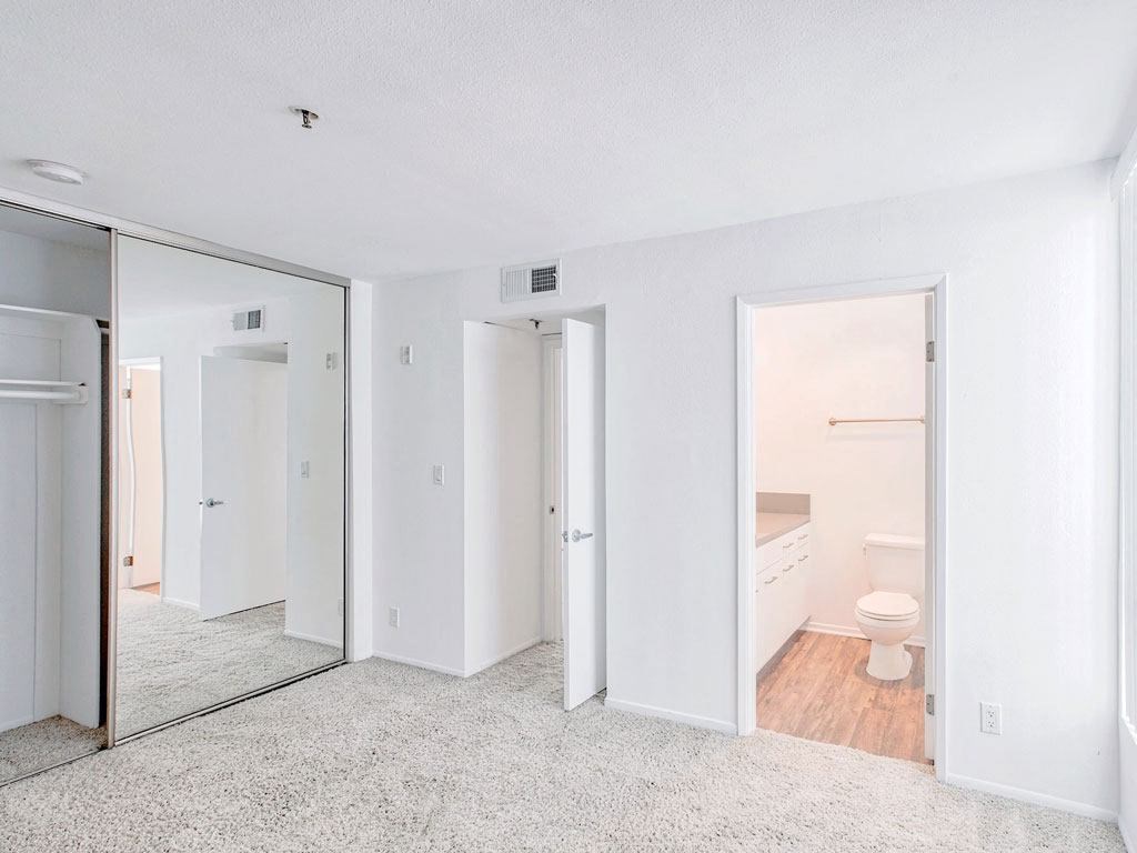 an empty room with a toilet and a mirror