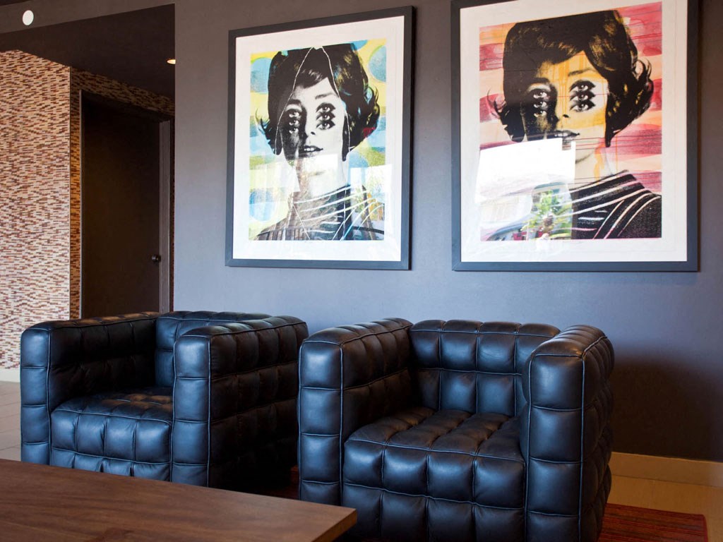 a living room with blue leather chairs and pictures on the wall