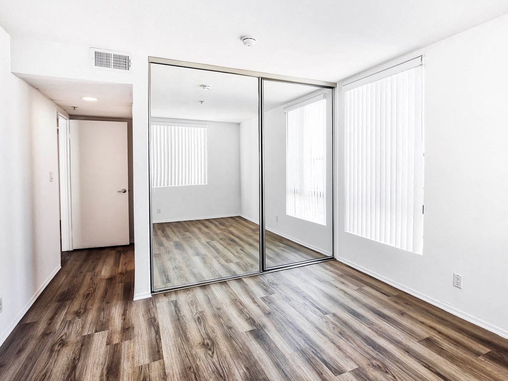 an empty living room with a large mirror and wood floors