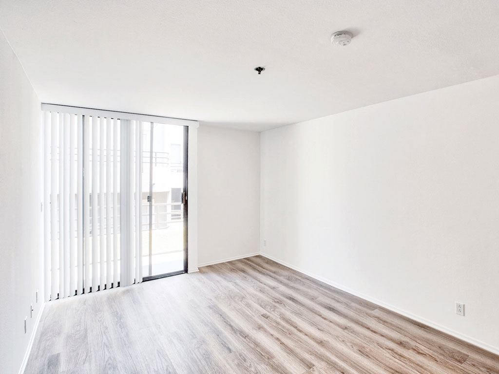 an empty living room with white walls and a sliding glass door