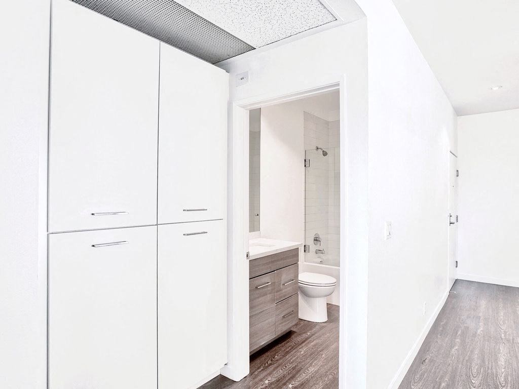 a white bathroom with white cabinets and a toilet
