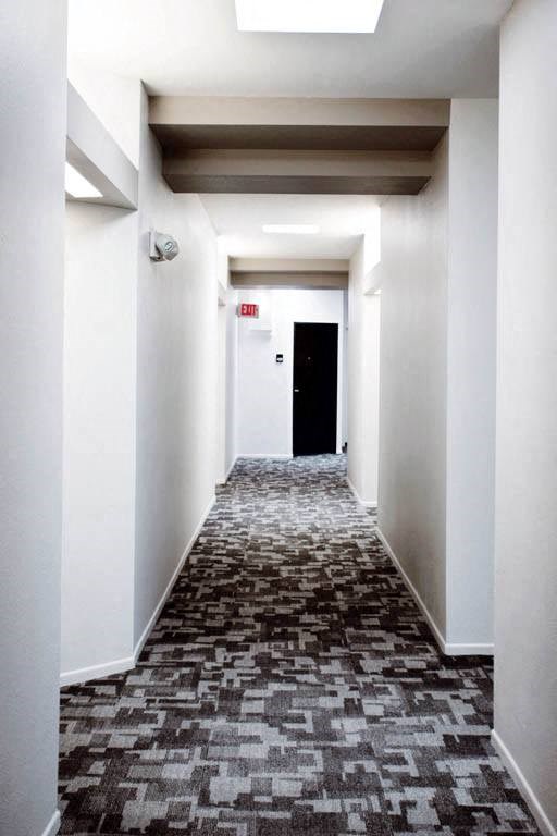 a long hallway with white walls and a black door