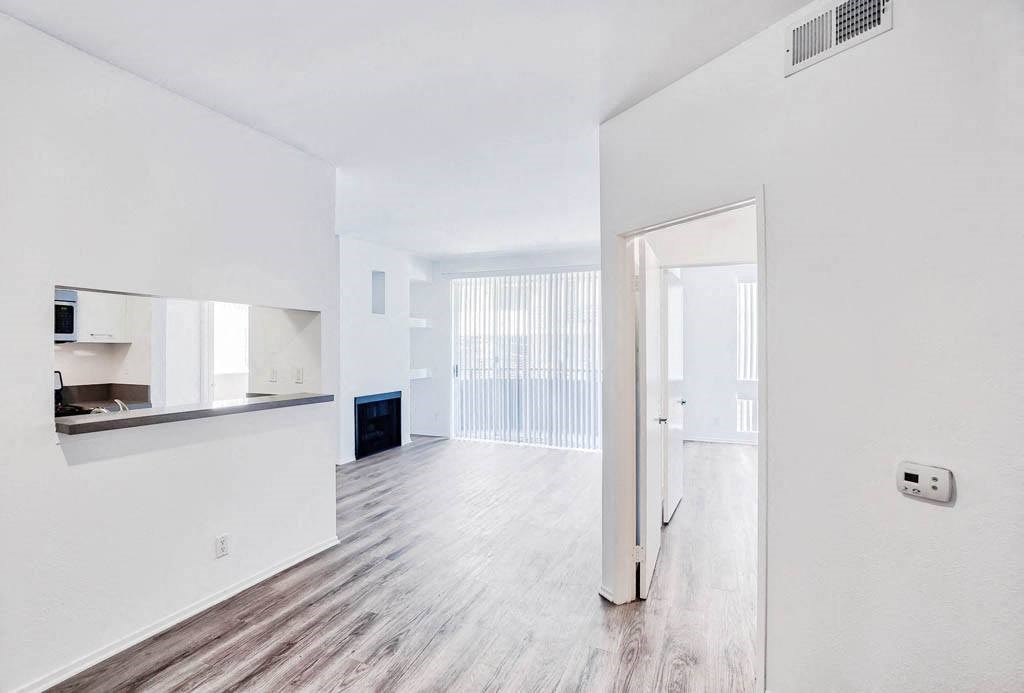 an empty living room and kitchen with white walls and wood floors