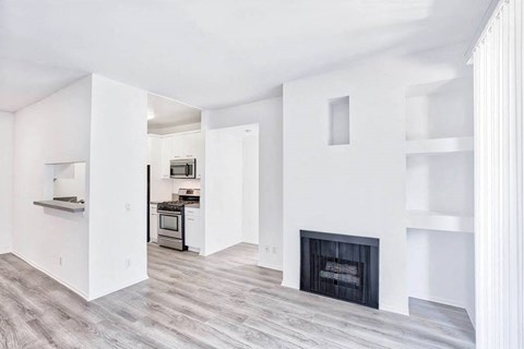 an empty living room with a fireplace and a kitchen
