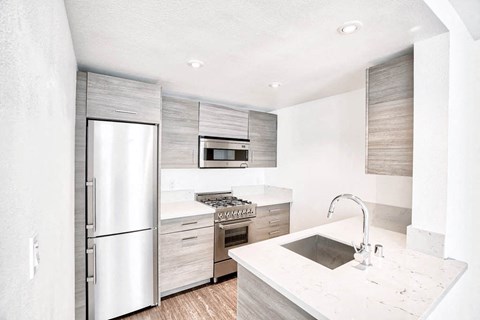 a white kitchen with stainless steel appliances and a sink