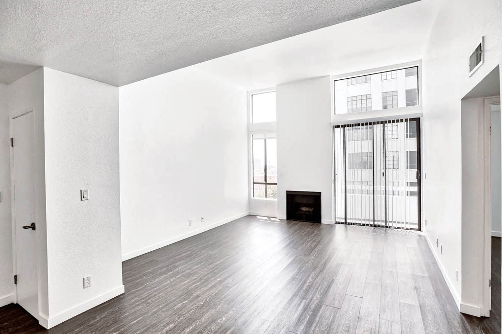 an empty living room with hard wood floors and a fireplace