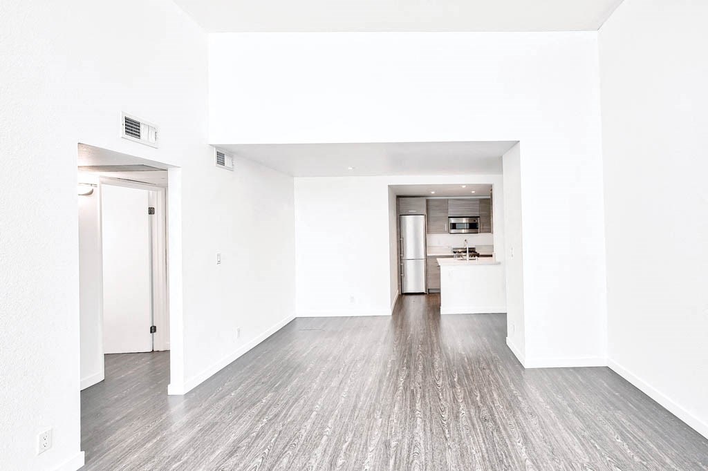 an empty living room with white walls and wood floors