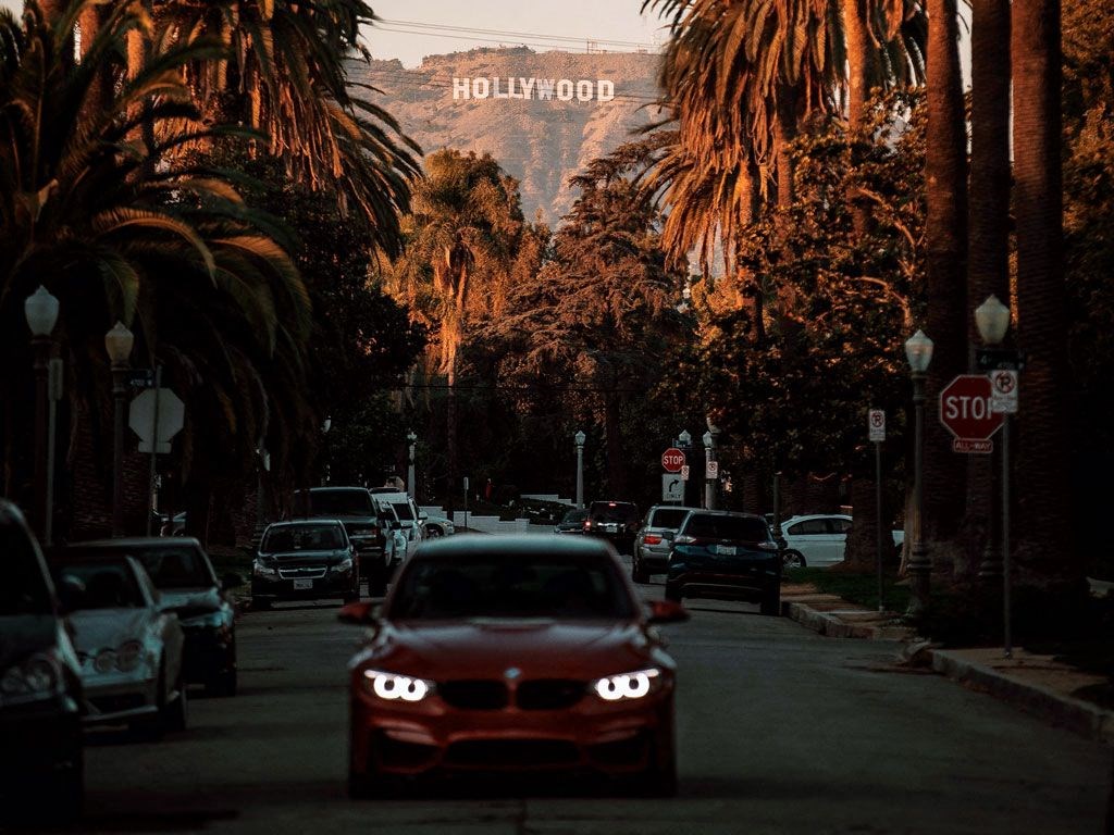 a red car driving down a street with palm trees