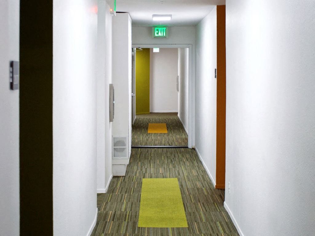 a hallway with rugs and an exit sign