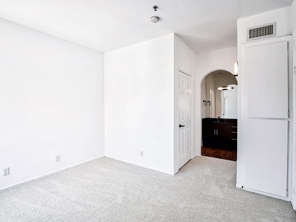 an empty room with white walls and a white refrigerator