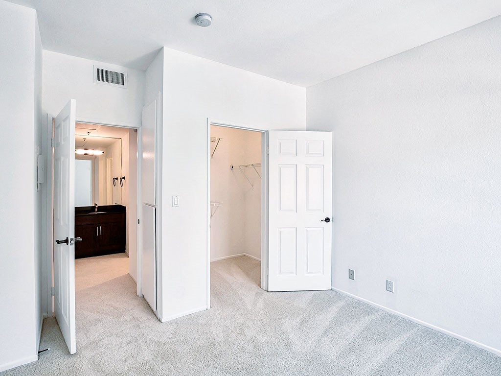 an empty bedroom with a closet and a door to a bathroom