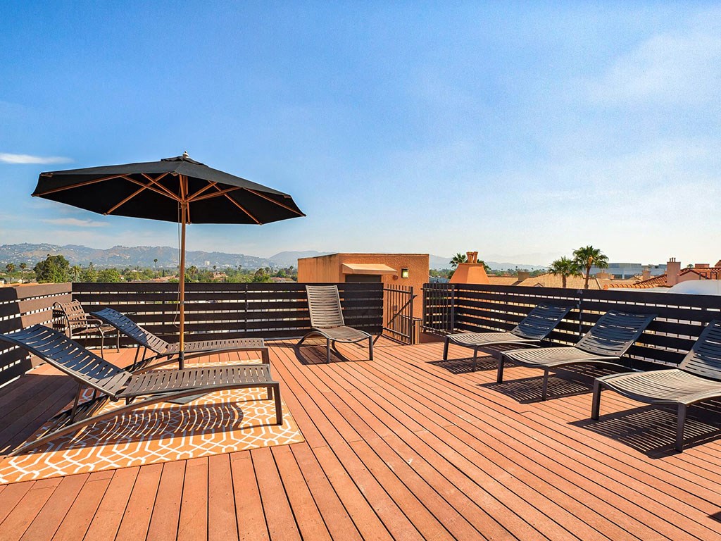 the deck on the top of the building has chairs and an umbrella