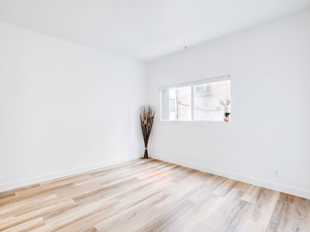a room with white walls and a window and wood floors