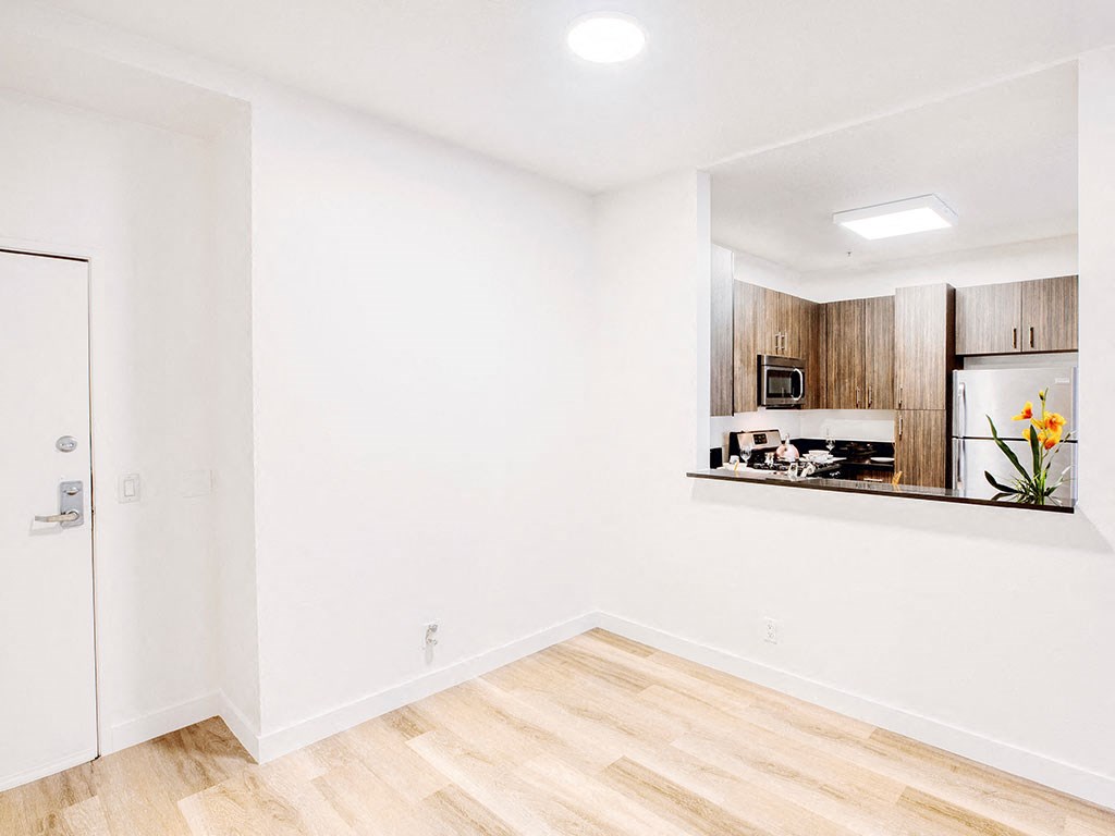 an empty living room with a kitchen in the corner