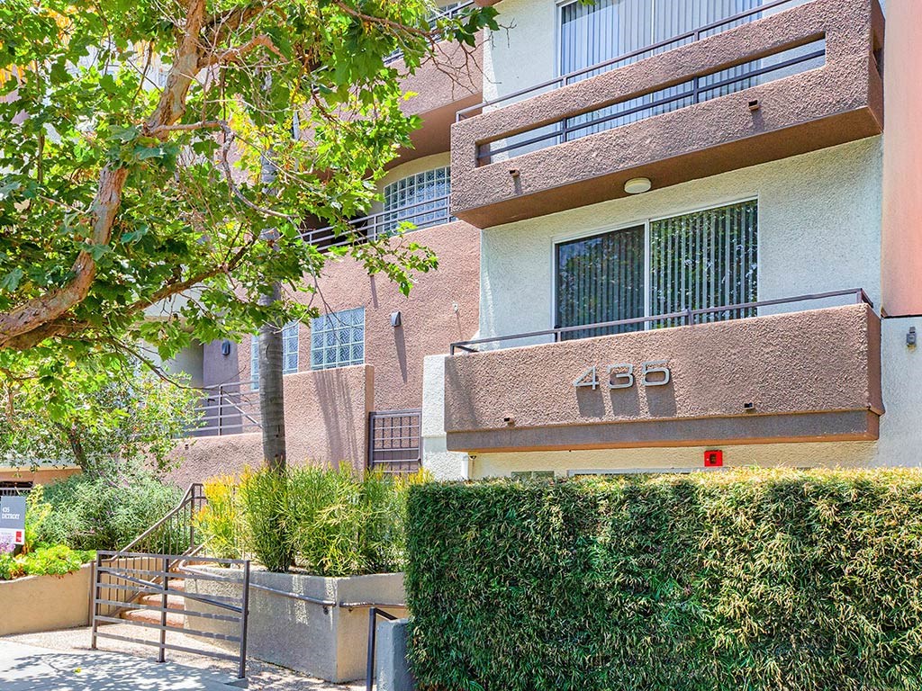 an apartment building with hedges and a staircase