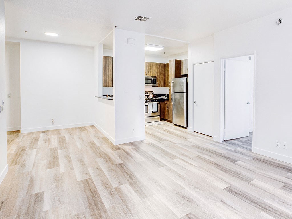 a renovated living room with wood flooring and a kitchen