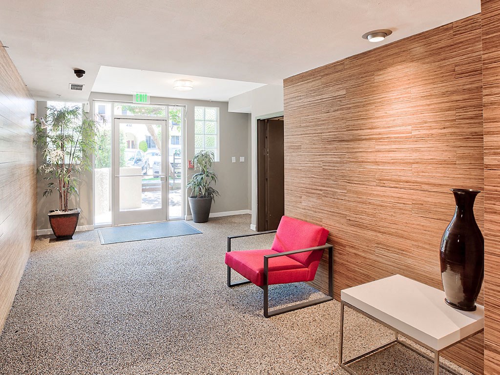 a lobby with a red chair and a wooden wall and a door