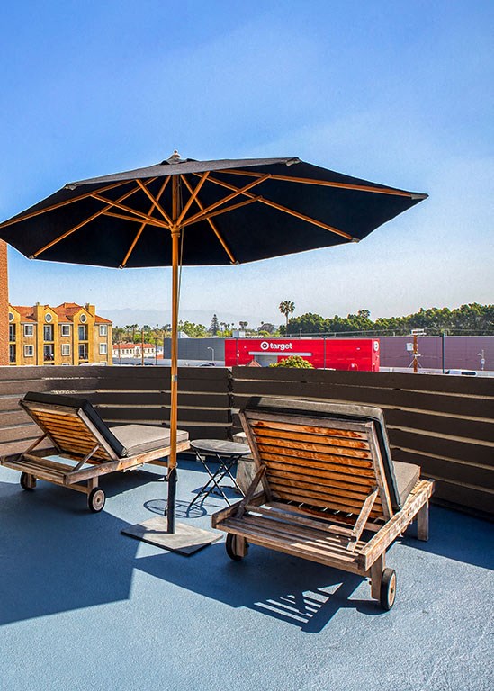 two lounge chairs under an umbrella on a roof