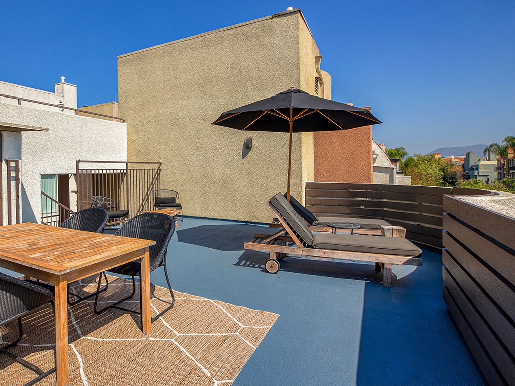 a rooftop patio with an umbrella and chairs and a table