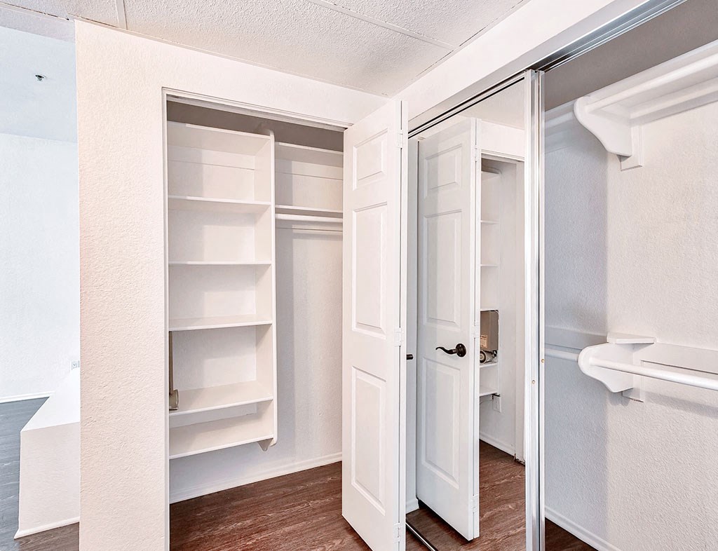 a walk in closet with a mirrored door and shelves