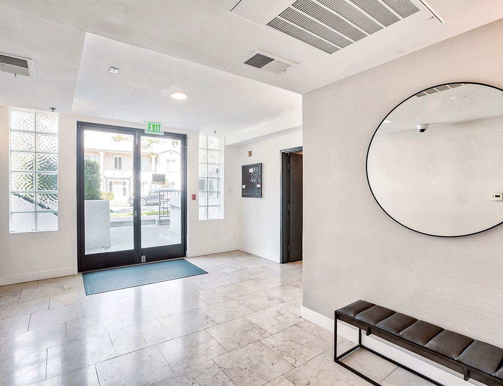 a lobby with a round mirror and a glass door