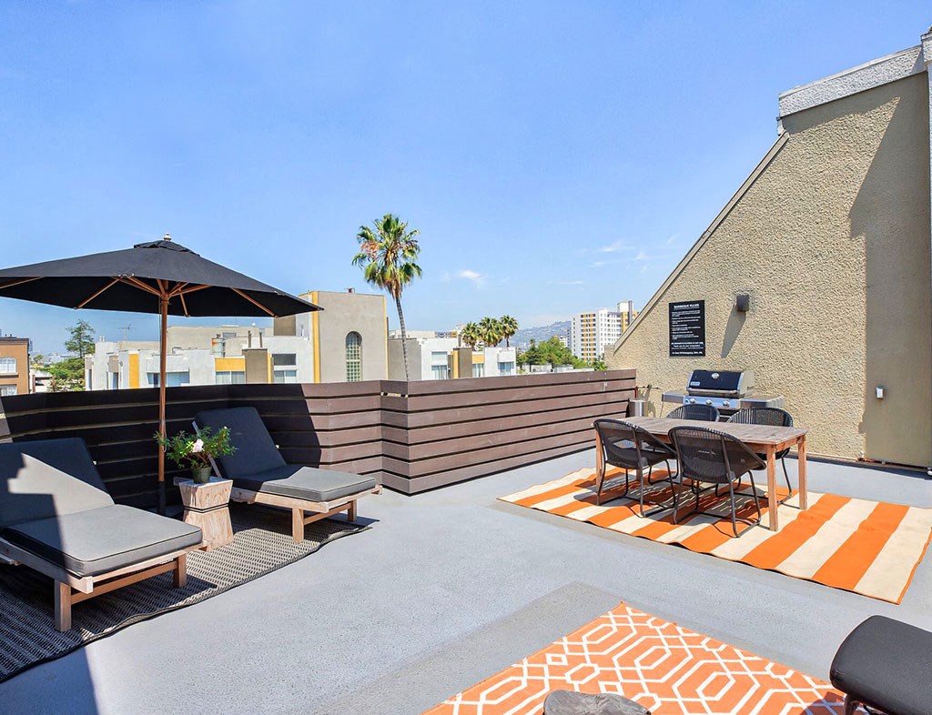 a rooftop patio with a table and chairs and an umbrella