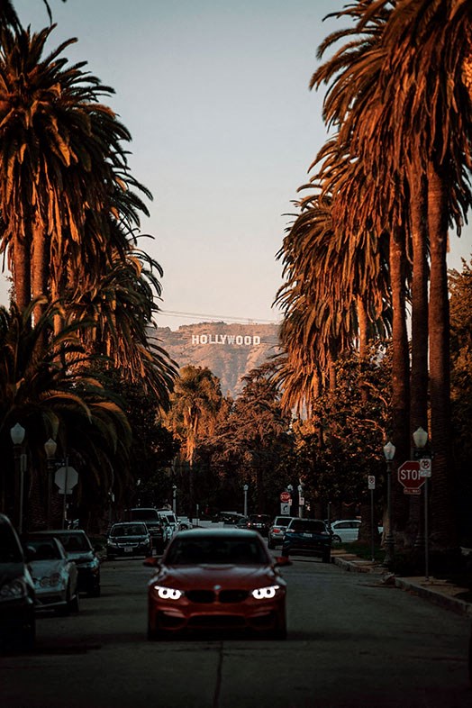 a red car driving down a street with palm trees