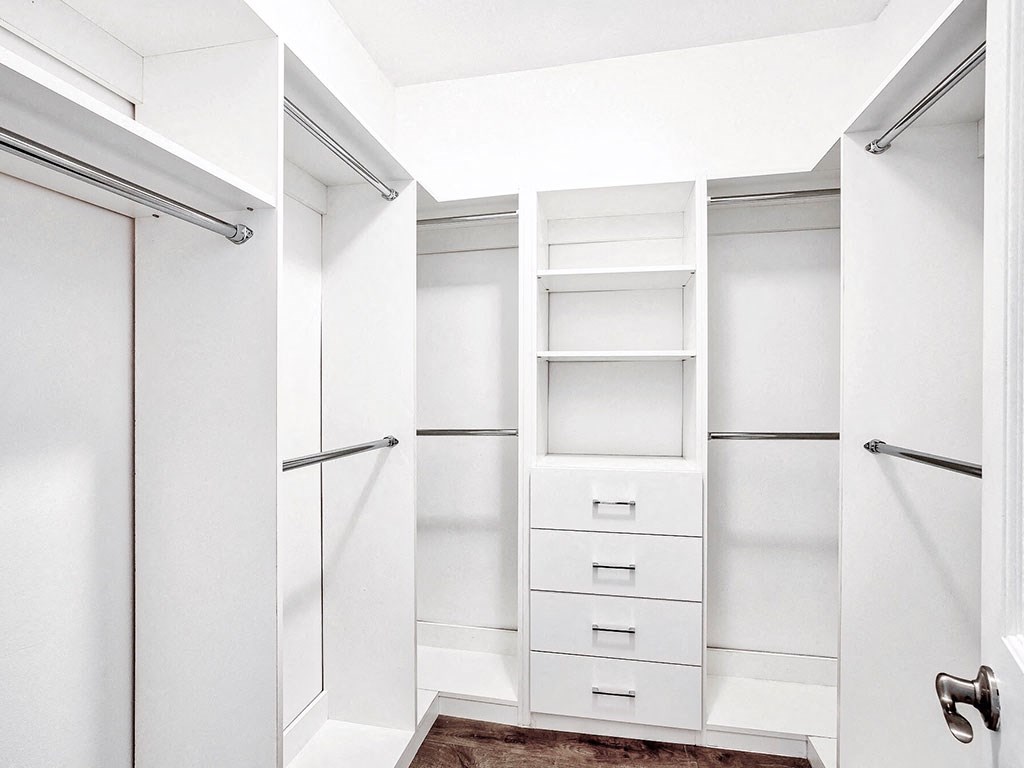 a walk in closet with white cabinets and white drawers