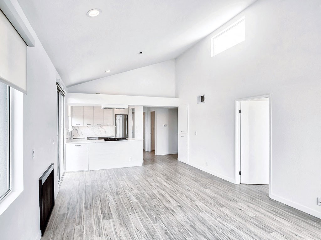 the living room and kitchen of a new home with white walls and wood flooring