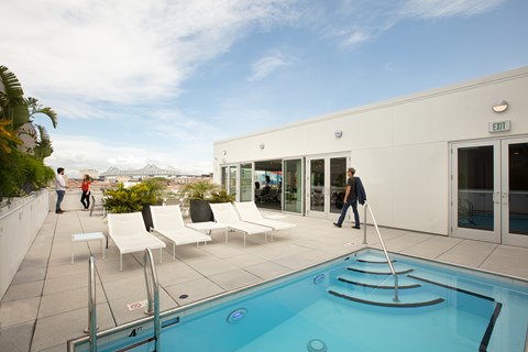 A man is walking towards a pool on a sunny day.