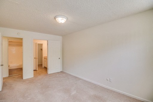 an empty living room with a bathroom in the background