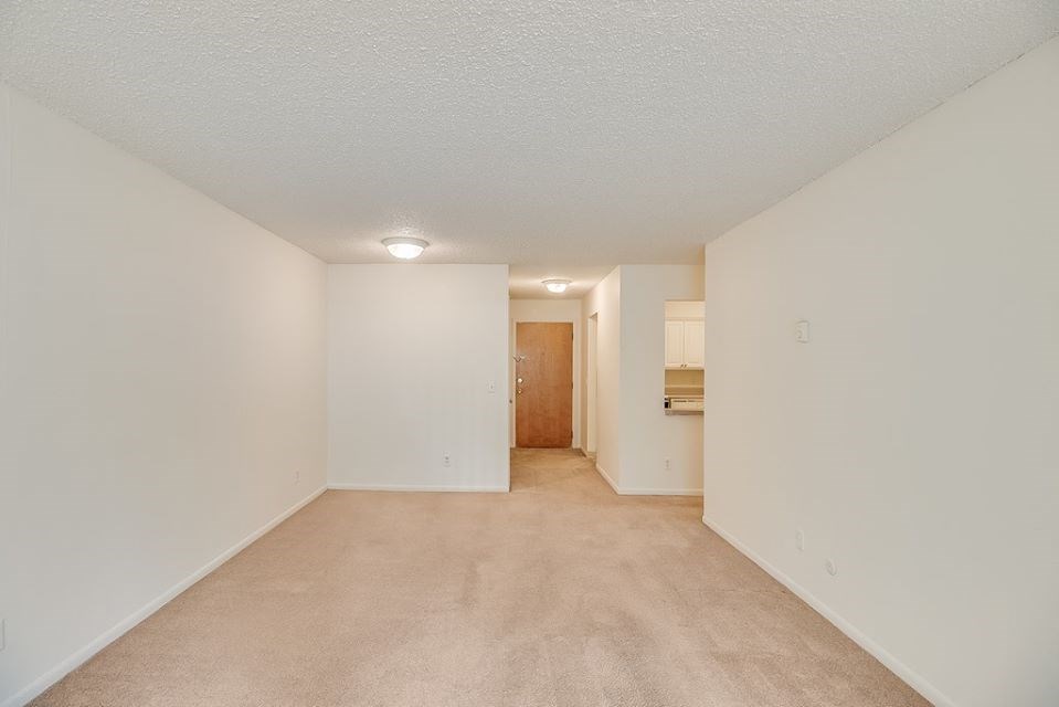 the spacious living room and kitchen of an apartment