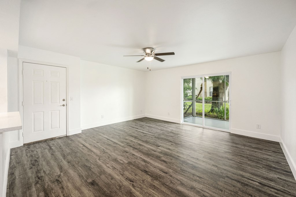 an empty living room with a ceiling fan and a window