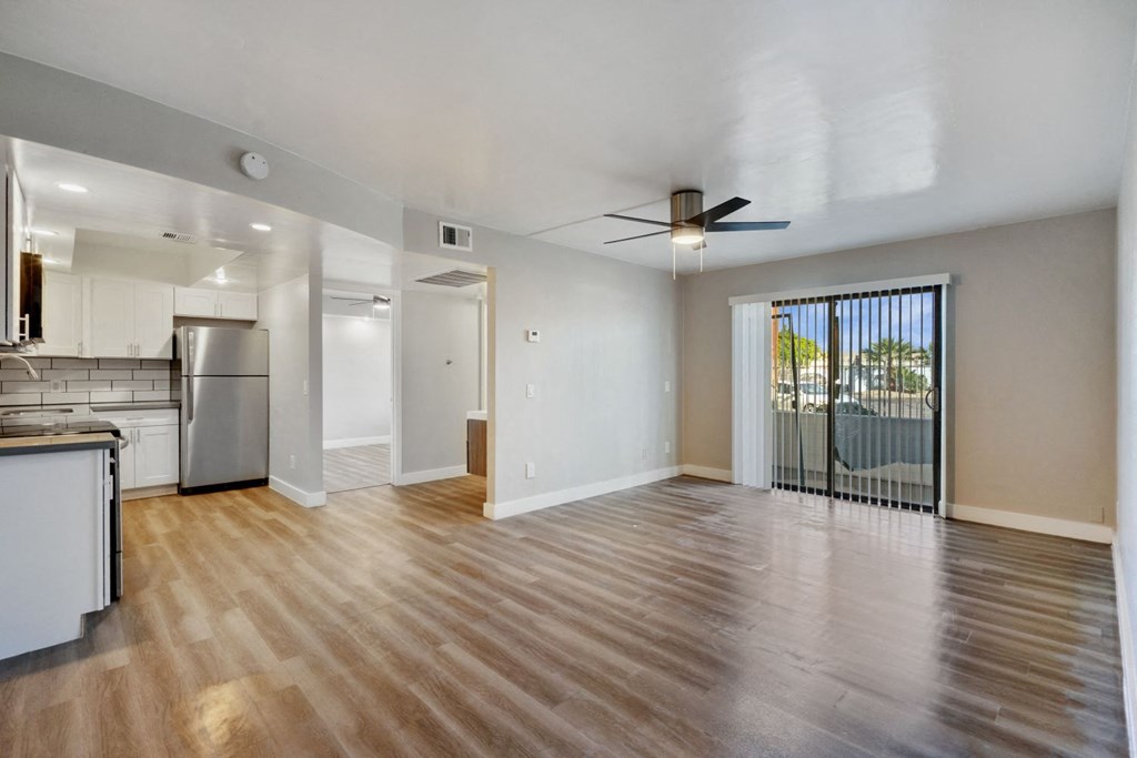 an empty living room with a sliding glass door leading to a balcony