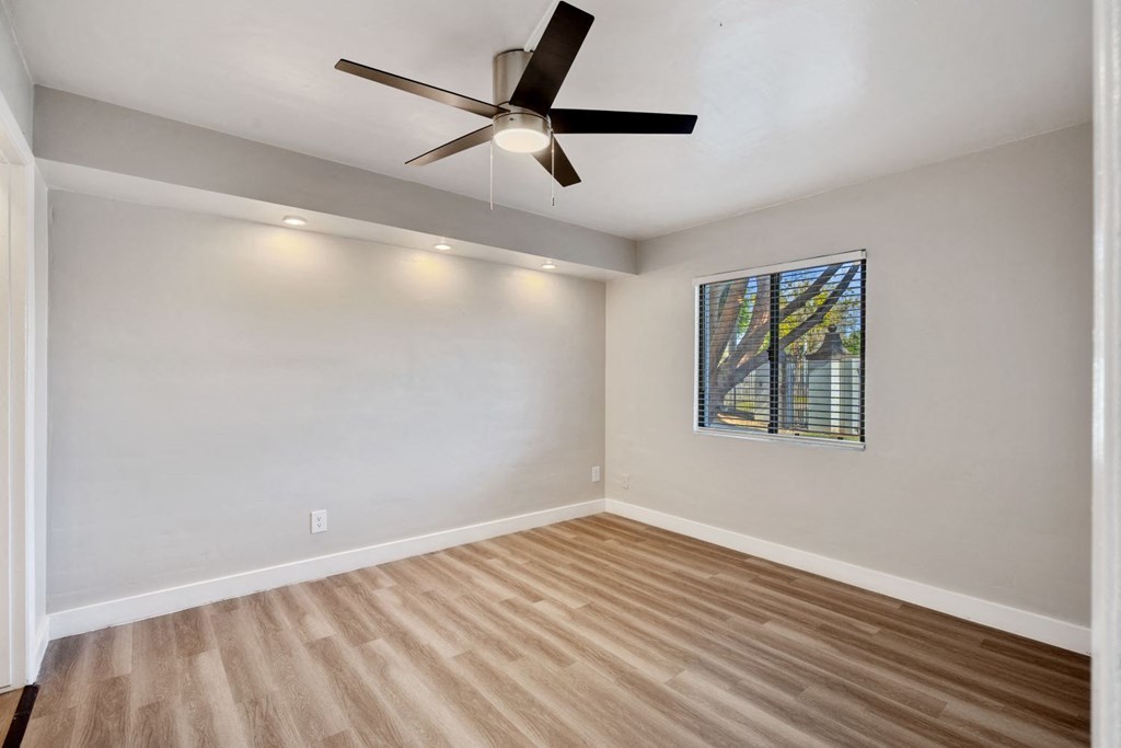 an empty room with a ceiling fan and a window