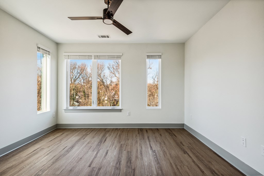an empty room with white walls and wooden floors and a ceiling fan